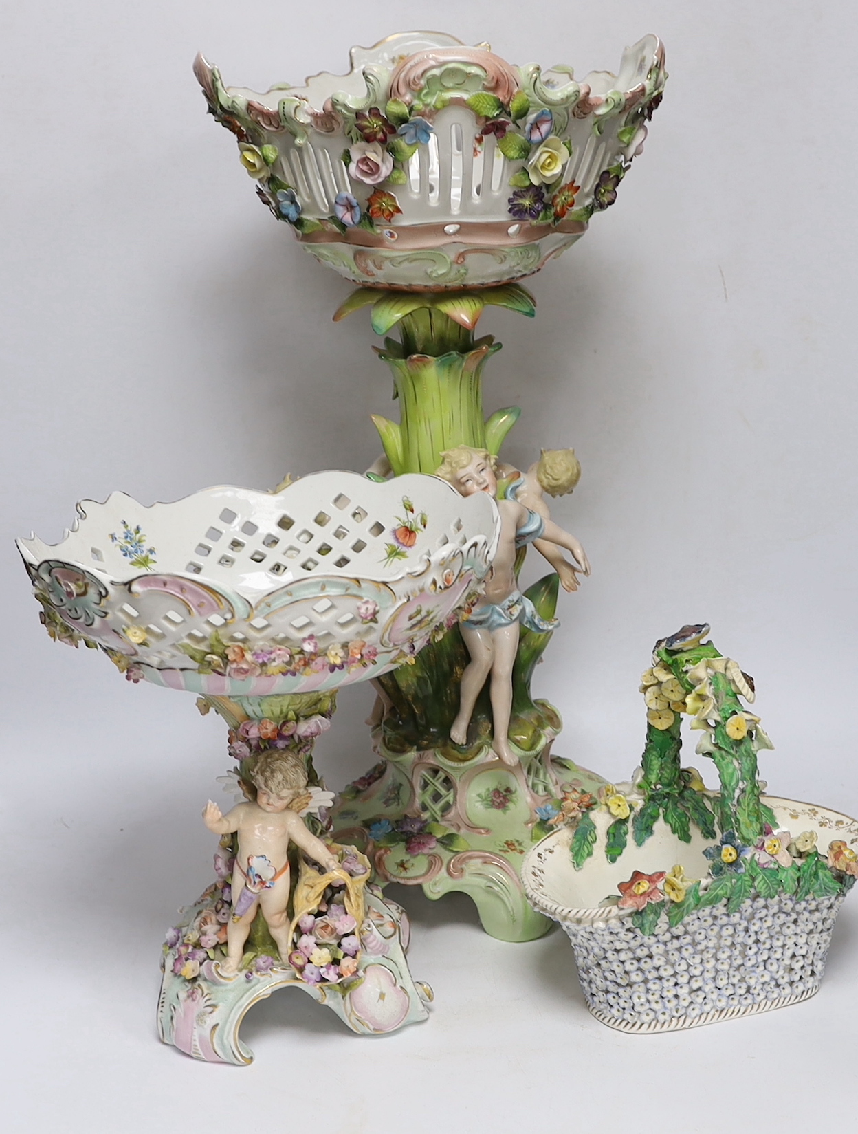 A Sitzendorf figural centrepiece, a smaller similar centrepiece and an English porcelain basket, tallest 54cm